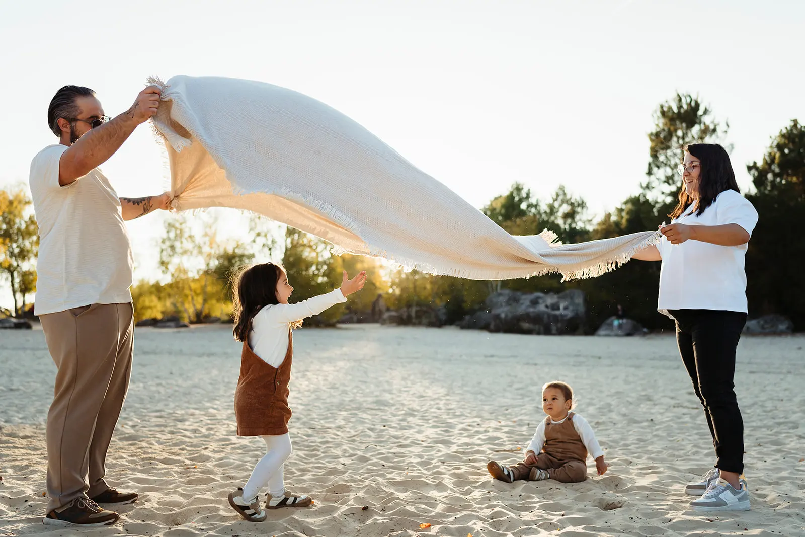 Photo colorée au coucher du soleil de parents jouant avec leurs enfants pendant une séance photo famille dans la forêt de Fontainebleau