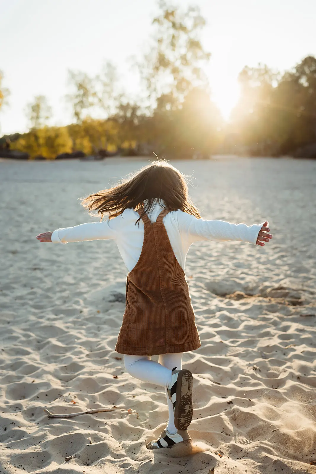 Photo colorée au coucher du soleil d'une petite fille qui danse pendant une séance photo famille à Fontainebleau