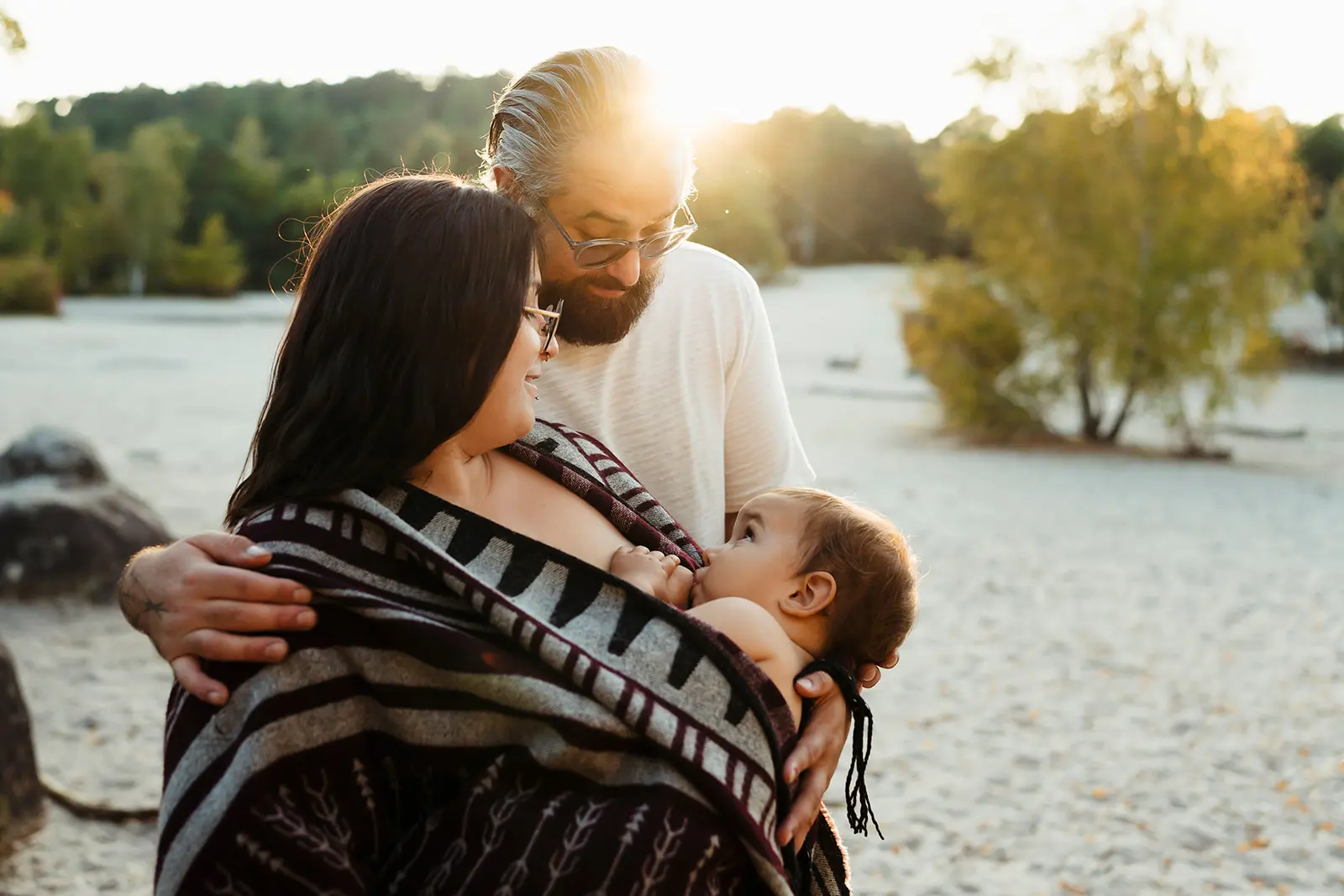 Photo de parents dans un moment de complicité avec leur bébé à Fontainebleau pendant que la maman donne le sein à son enfant