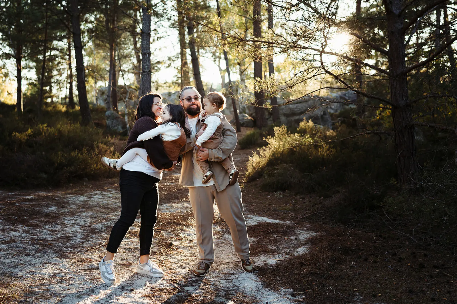 Image colorée et fun d'une famille jouant avec les enfants dans la forêt de Fontainebleau pendant une séance photo famille