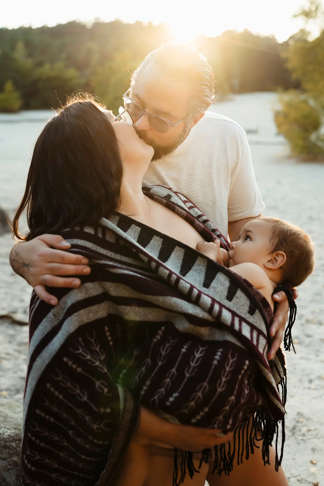 Maman allaitant son bébé en forêt de fontainebleau pendant une séance photo d'allaitement au coucher du soleil