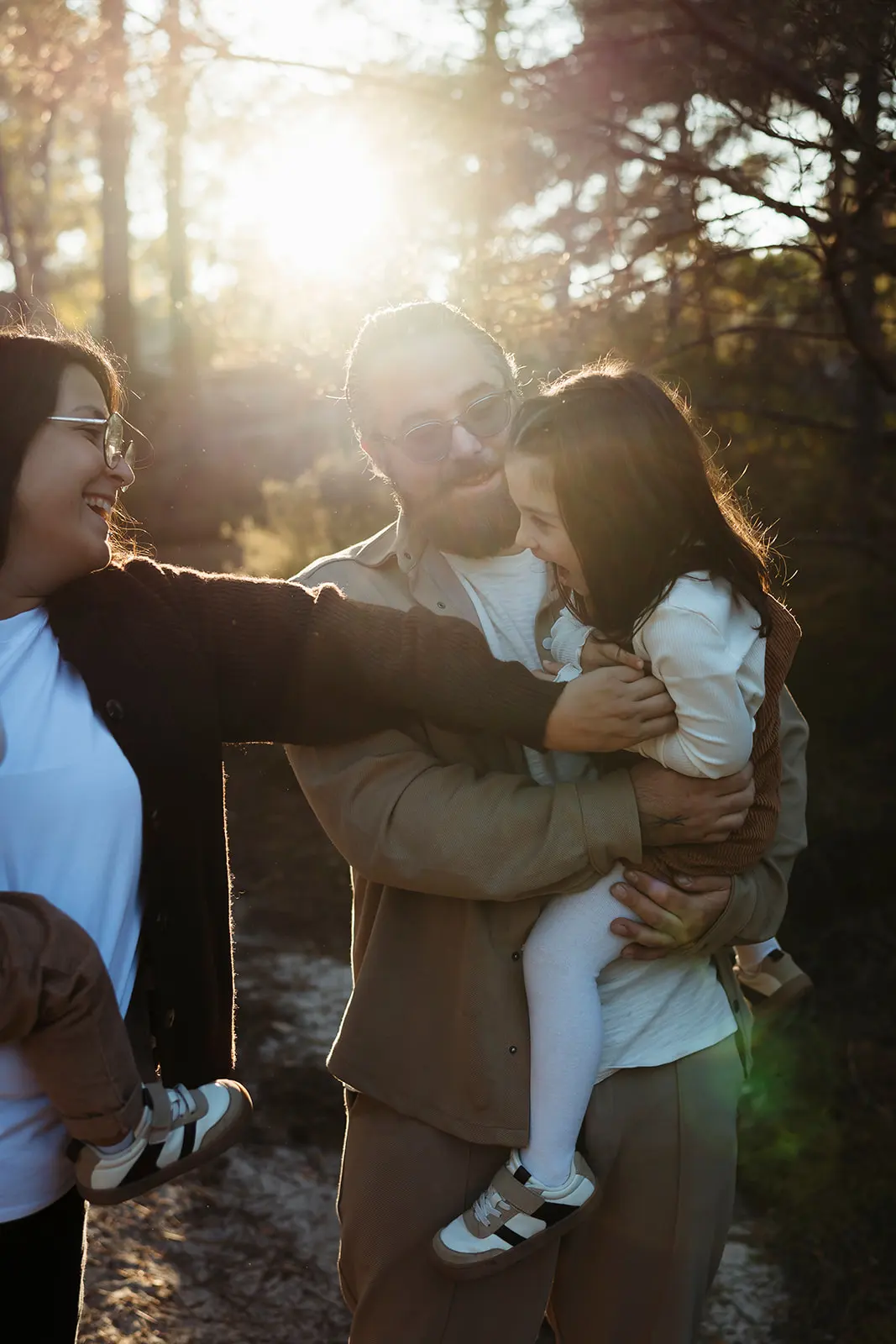 Photo colorée et spontanée d'une petite fille riant aux éclats quand sa maman la chatouille pendant une séance photo de famille à Fontainebleau