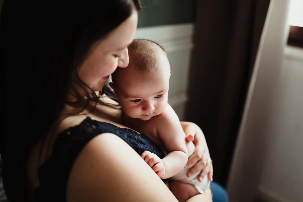 Photo colorée d'une maman en peau à peau avec son bébé pendant une séance photo naissance à domicile à Fontainebleau