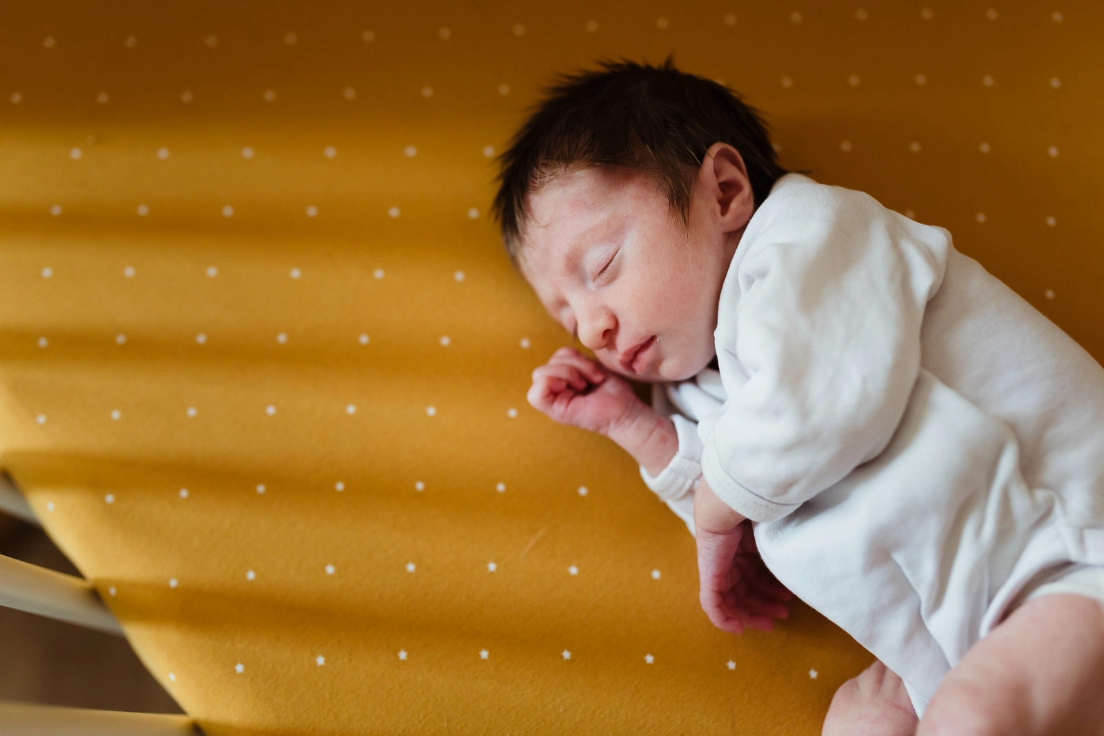 Portrait en couleur d'un nouveau-né dormant paisiblement dans son berceau pendant une séance photo de naissance à domicile à Fontainebleau