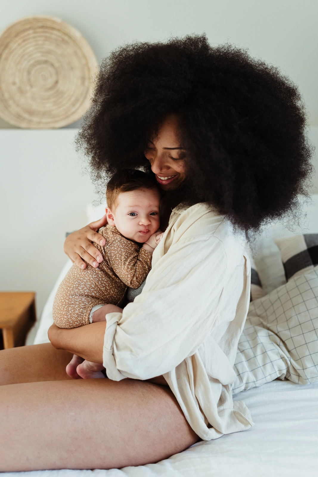 Photo couleur d'une maman métisse avec son bébé pendant un moment de tendresse après une tétée pendant une séance photo de naissance à domicile à côté de Fontainebleau