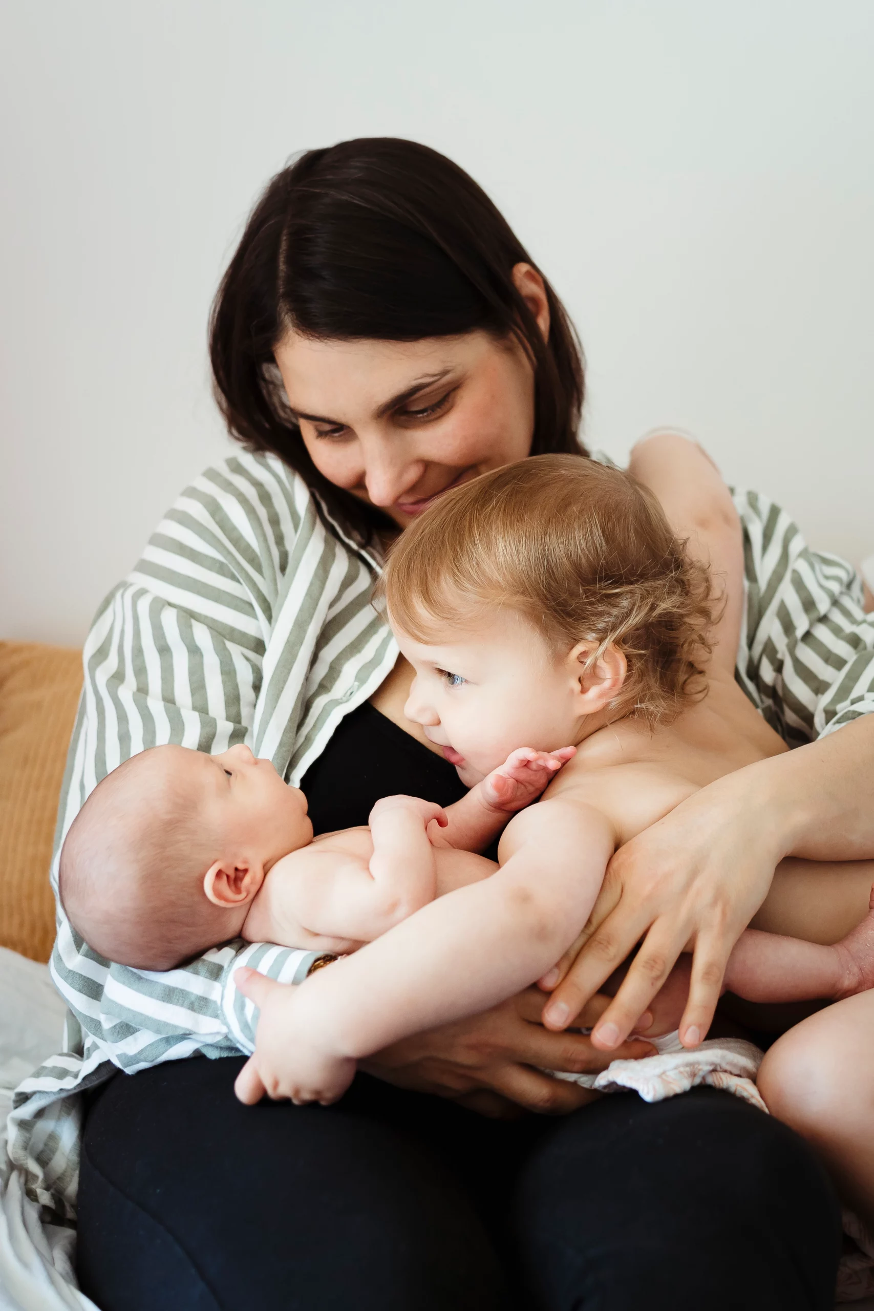 Portrait en couleur d'une mère, de sa fille aînée et de son nouveau-né pendant une séance naissance à domicile près de fontainebleau