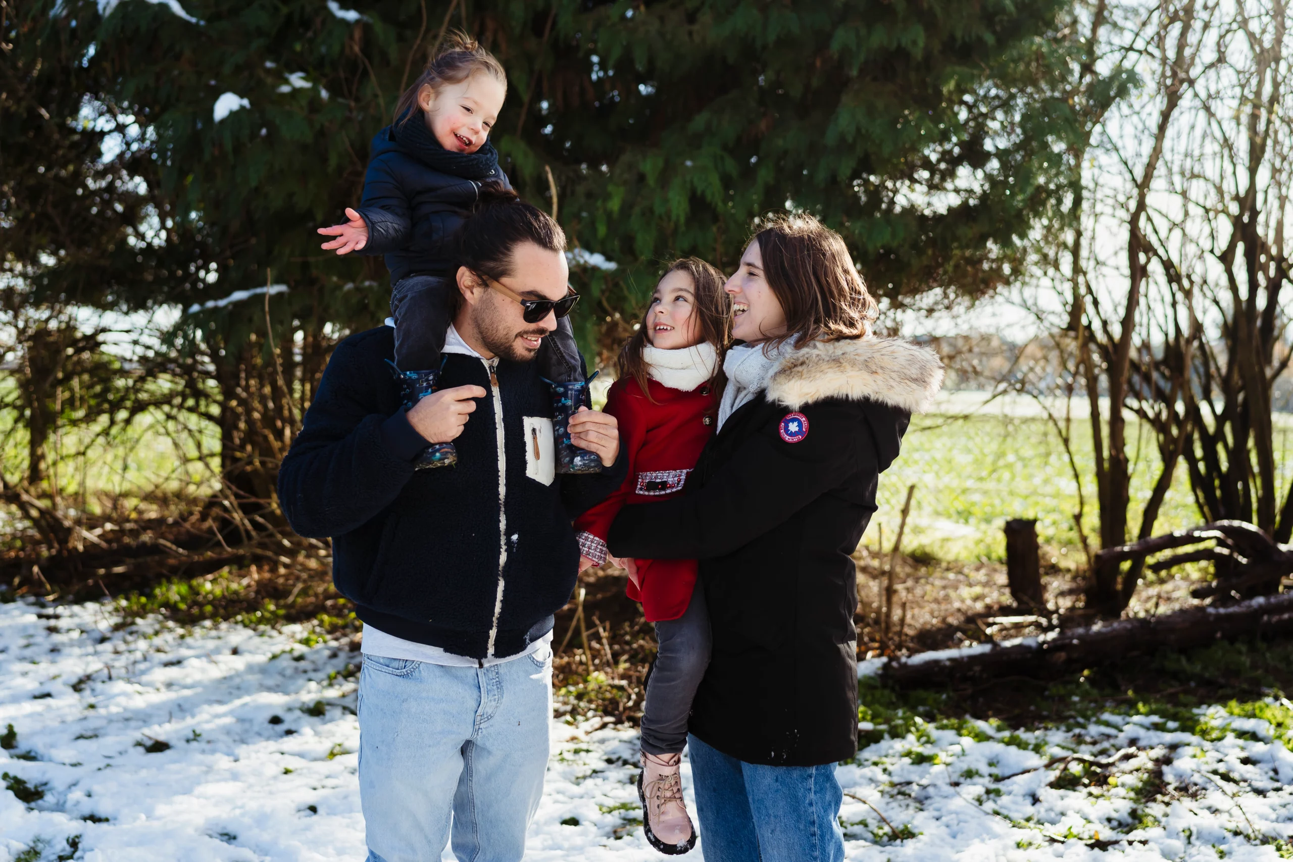 Photo de famille se faisant un câlin dans leur jardin à fontainebleau pendant une séance photo sous la neige