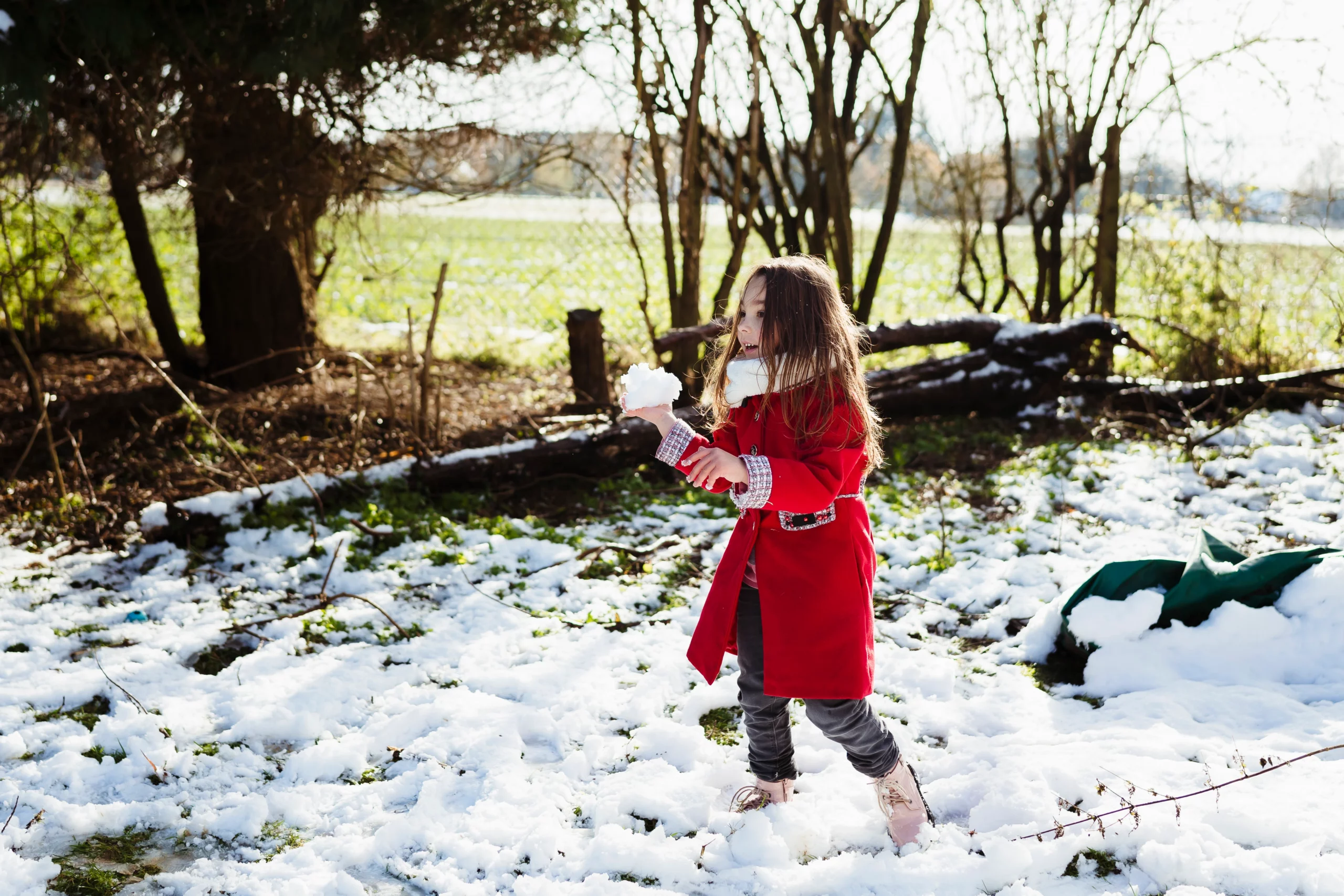 Photo d'une petite fille qui lance une boule de neige pendant une séance famille en seine et marne