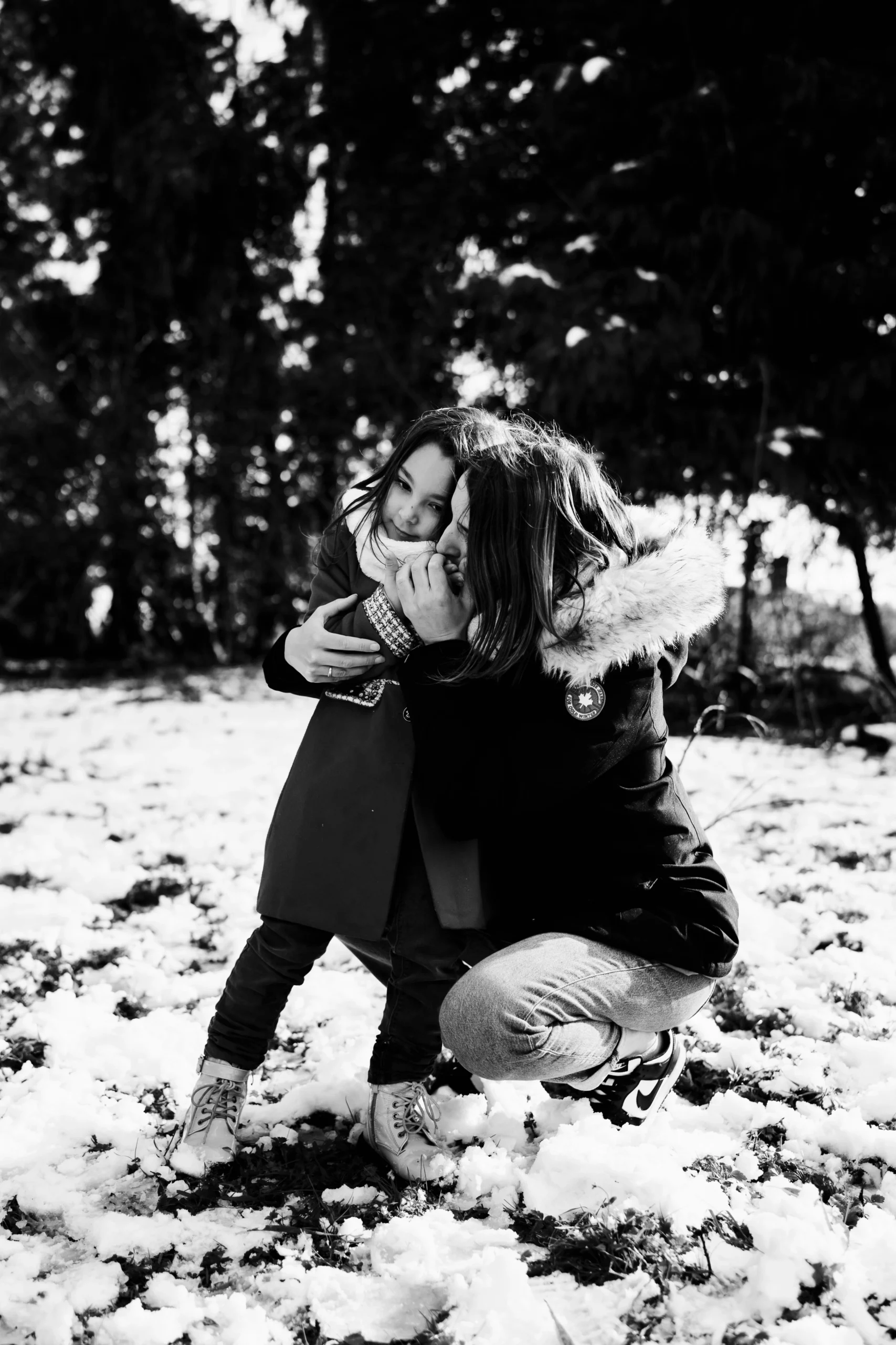 portrait noir et blanc d'une maman qui réchauffe les mains de sa fille pendant une séance photo famille sous la neige a fontainebleau