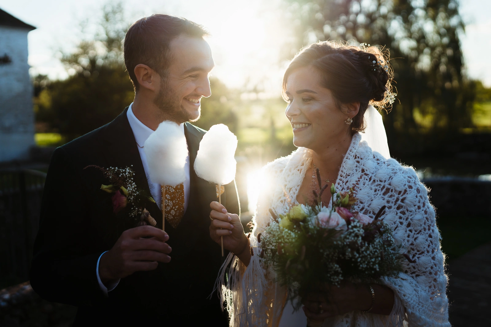 Photo d'un couple de mariés au couché du soleil dégustant une barde à papa pendant le cocktail de leur mariage alternatif à Fontainebleau