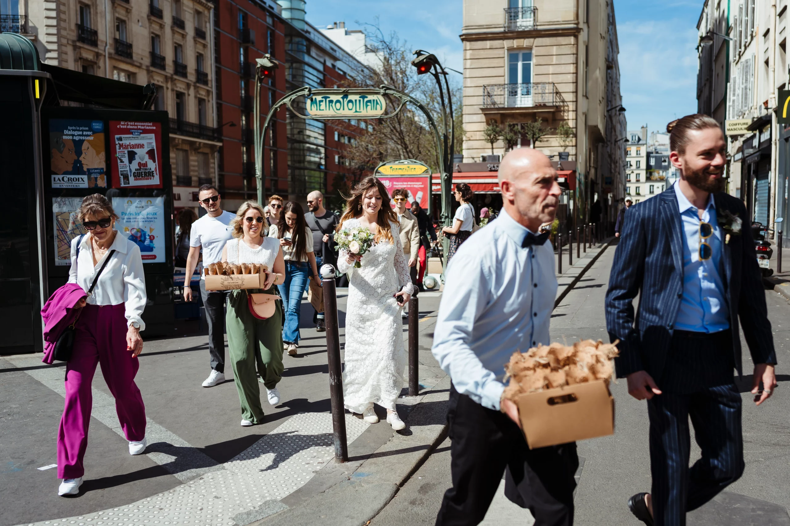 Mariés et leurs invités marchant dans les rues de paris pour se rendre à un mariage civil fun et coloré à la mairie du 11ème