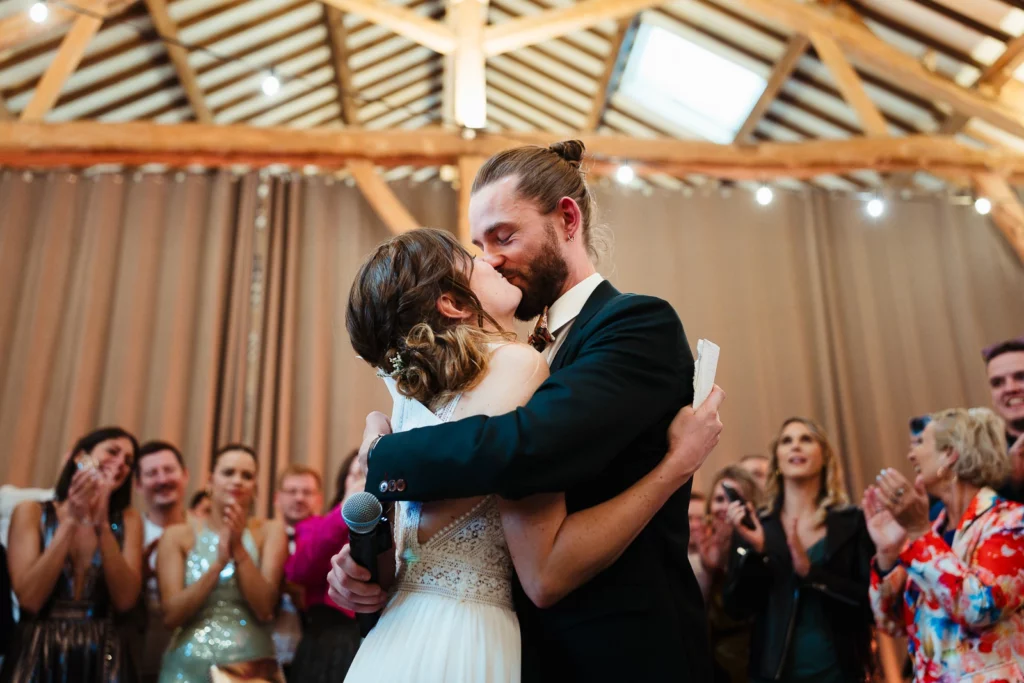 Couple de mariés s'embrassant après l'échange des voeux pendant leur mariage coloré au clos de Beaurepaire