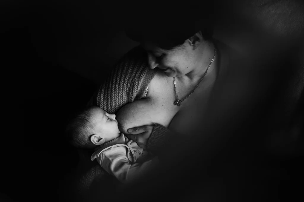 portrait en noir et blanc d'une mère donnant le sein à son fils pendant une séance photo nouveau-né à fontainebleau