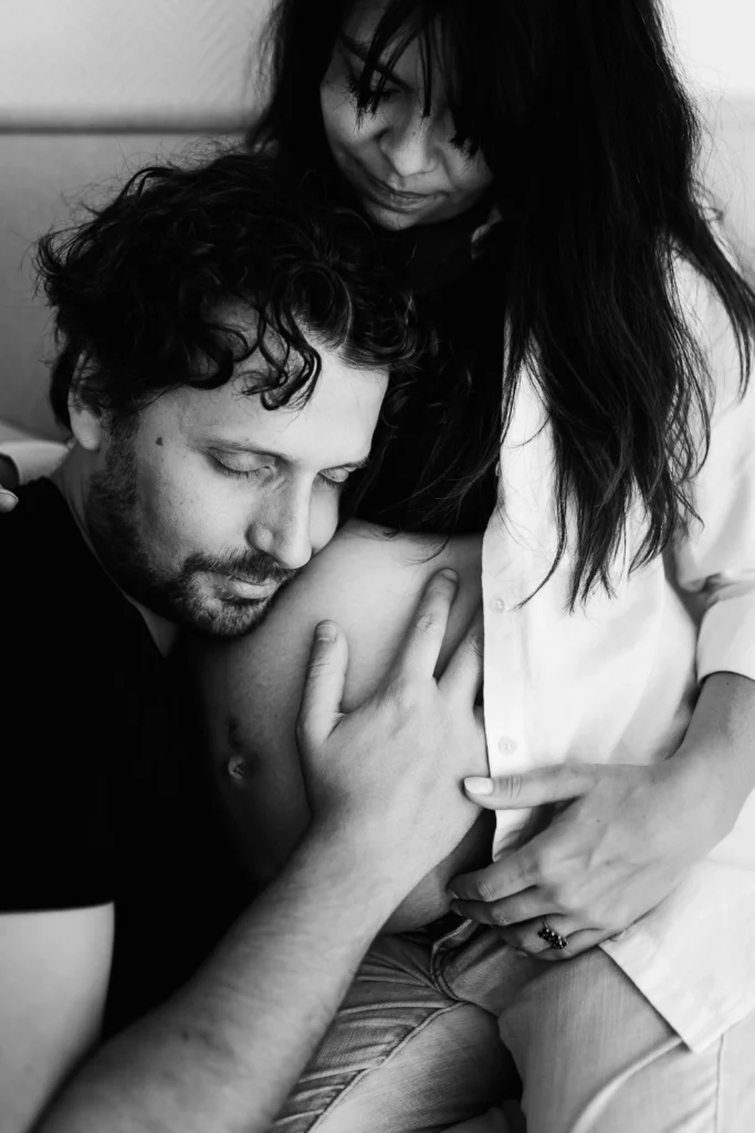 couple de futurs parents se faisant un câlin pendant une séance photo de grossesse à domicile à fontainebleau
