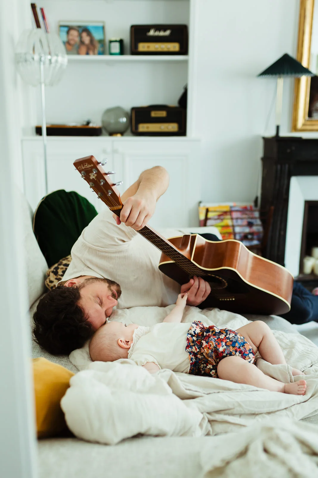 un papa qui joue de la guitare pour sa fille pendant une séance photo de naissance