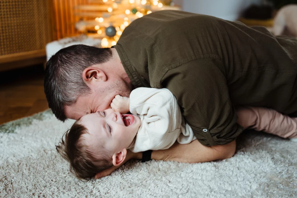 Photo natuelle et colorée d'un enfant riant avec son papa pendant une séance photo de famille à fontainebleau