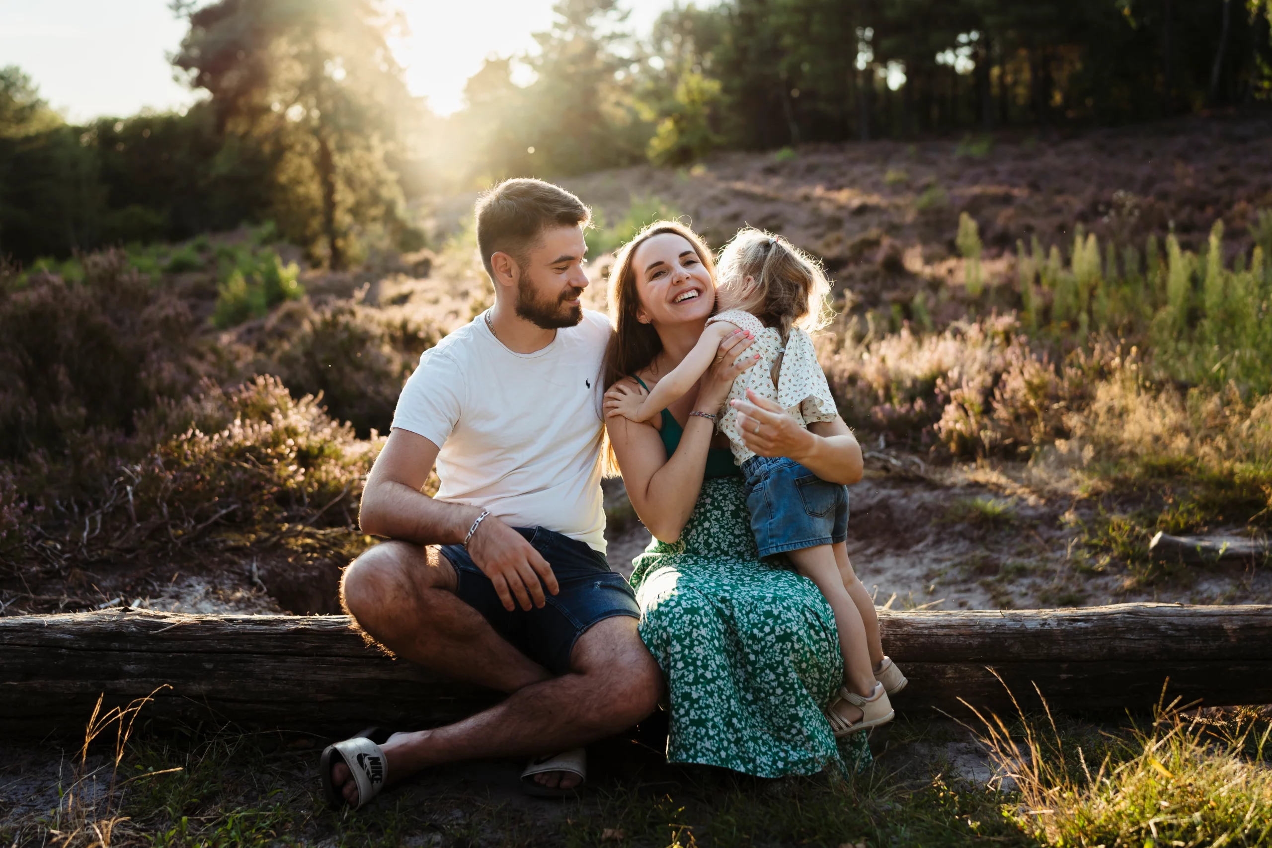 Photo d'une enfant au couché de soleil faisant un câlin à ses parents pendant une séance photo de famille en forêt de Fontainebleau