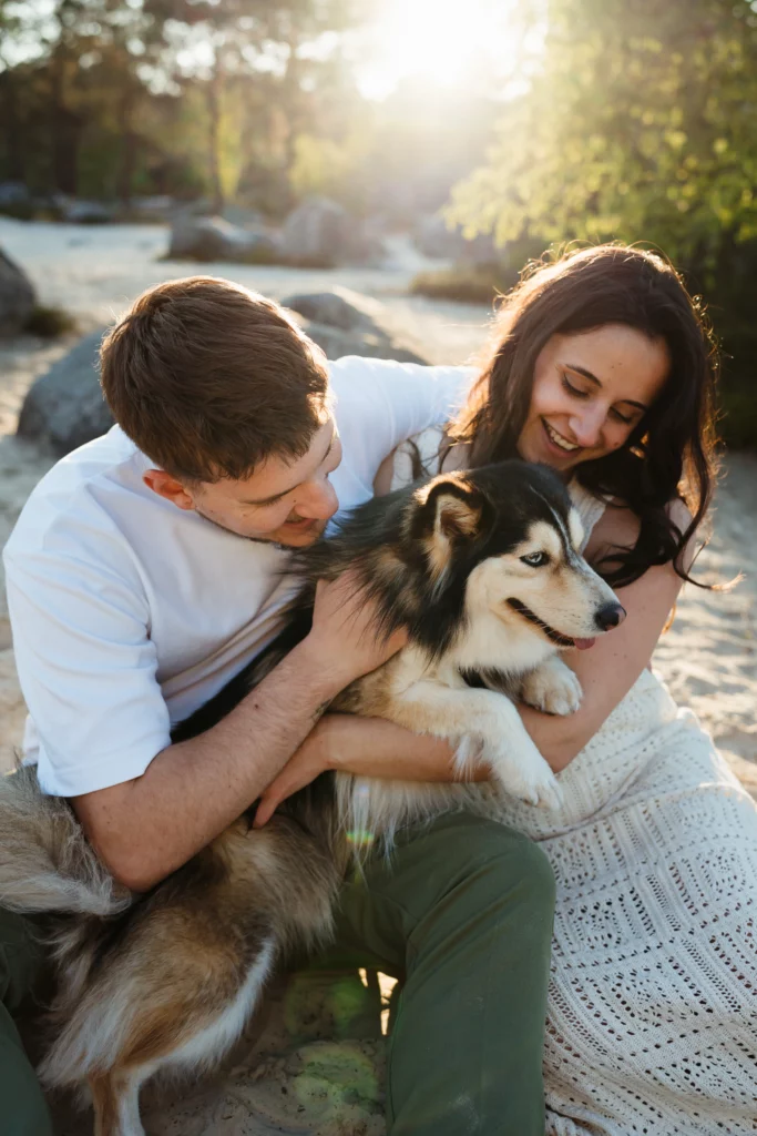 couple de futurs mariés qui caresse leur chien pendant une séance photo au coucher du soleil à fontainebleau