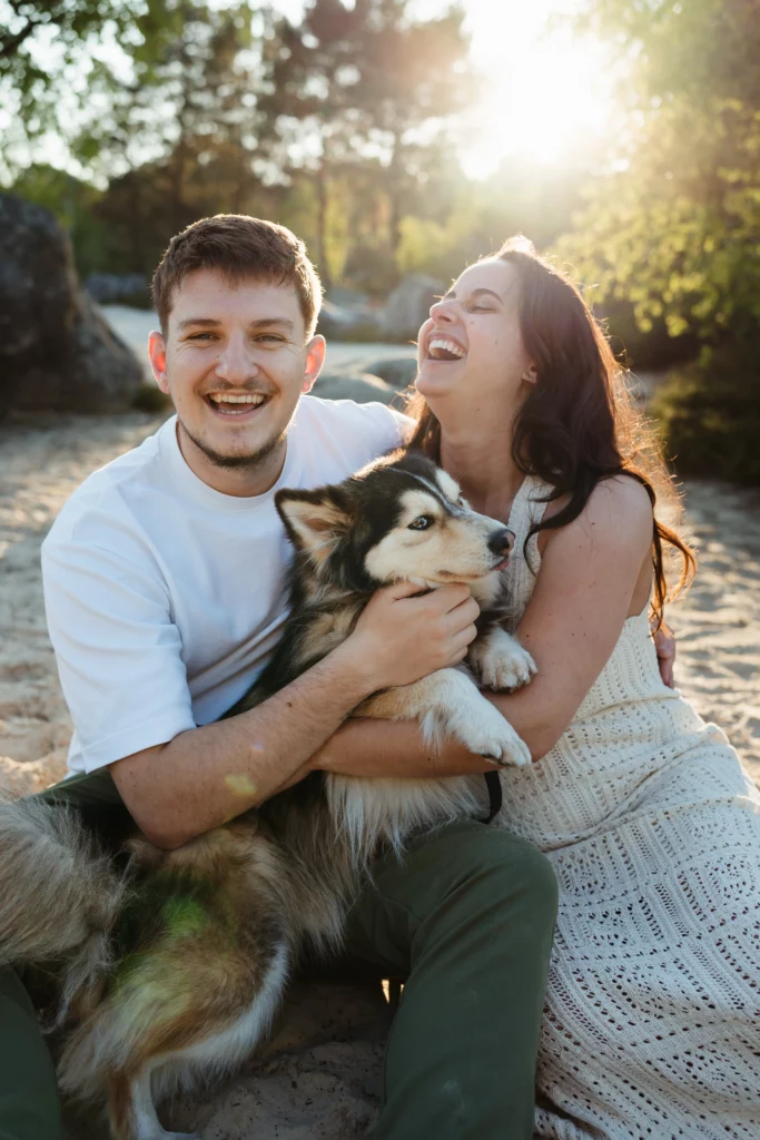 couple qui rient aux éclats pendant une séance photo engagement dog friendly à fontainebleau