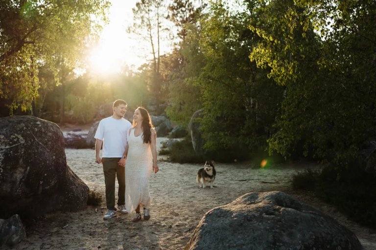 couple marchant au coucher du soleil avec leur chien dans la forêt de fontainebleau pendant une séance engagement