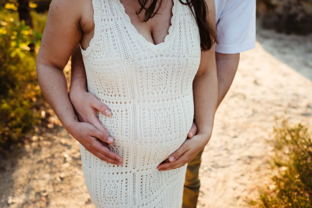 Ventre d'une femme enceinte pendant une séance photo de couple au coucher du soleil