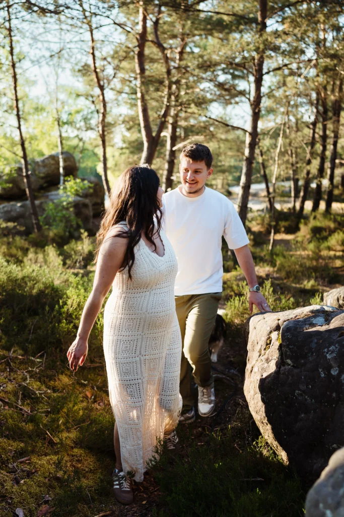 couple amoureux marchant dans la foret de fontainebleau pendant une séance engagement avant leur mariage