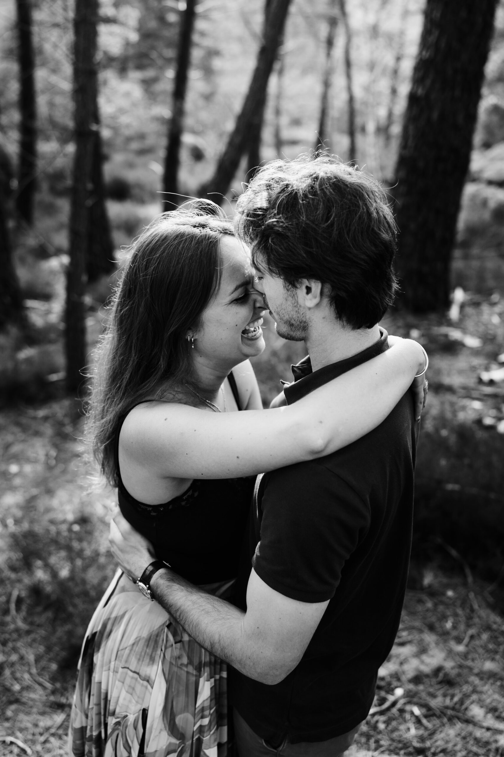 Couple riant aux éclats entre les pins de la forêt de Fontainebleau pendant une séance photo